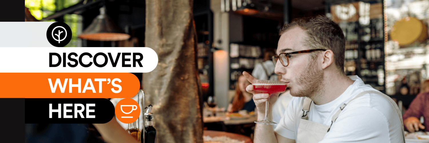 A man sitting at a cafe sipping a drink. A graphic is overlaid in orange and black, saying "DISOCER WHAT'S HERE" in white.