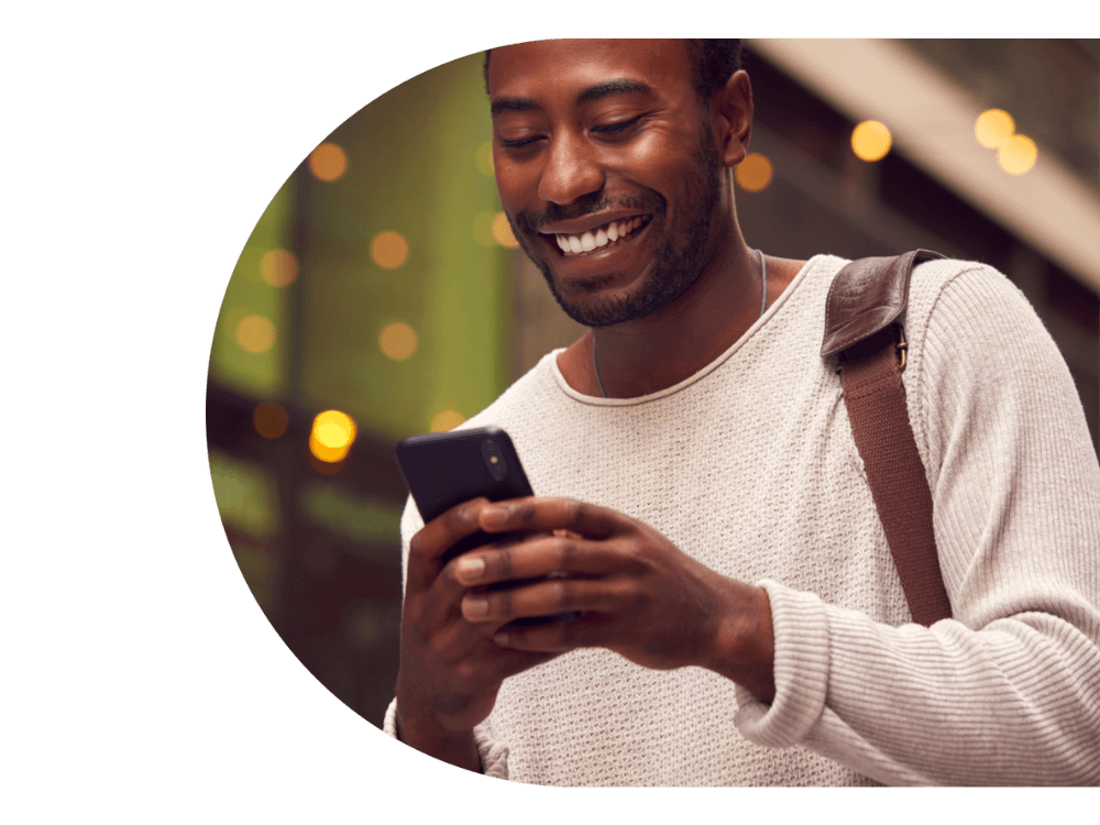 A man smiling and looking at his phone.